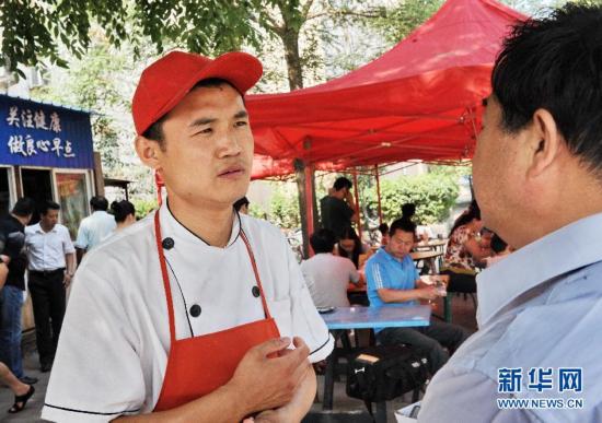 5月25日,刘洪安卖完油条后在小店外征求市民的意见.