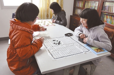 将乐万安学校的寄宿孩子在课外活动室里下棋.