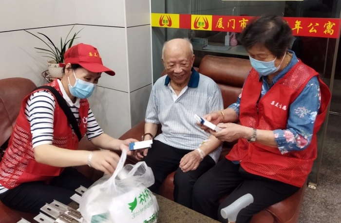 夕阳美志愿服务队老年志愿者为爱欣老年公寓的老人送药(诚毅志愿者联盟供图).jpg
